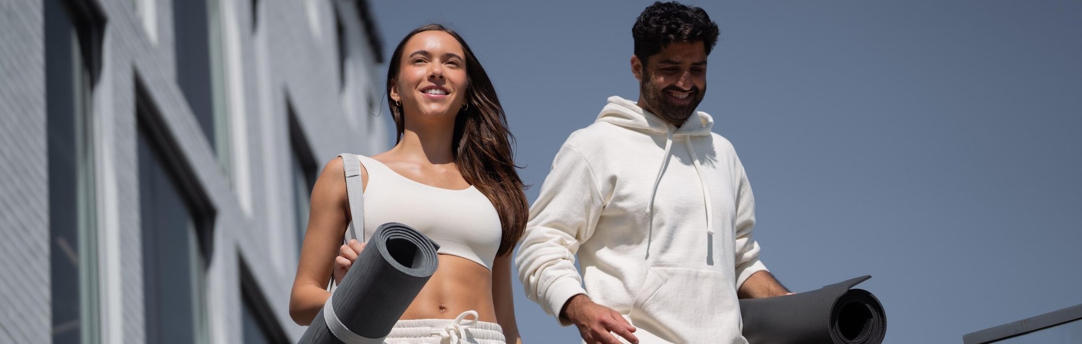 Two people walking with practice mats in the city