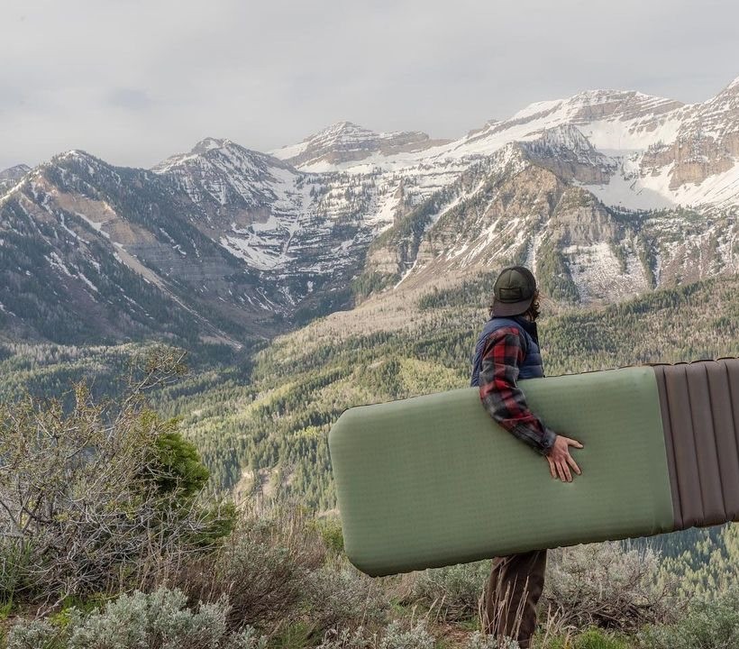 Hiker carrying a sleeping pad in the mountains